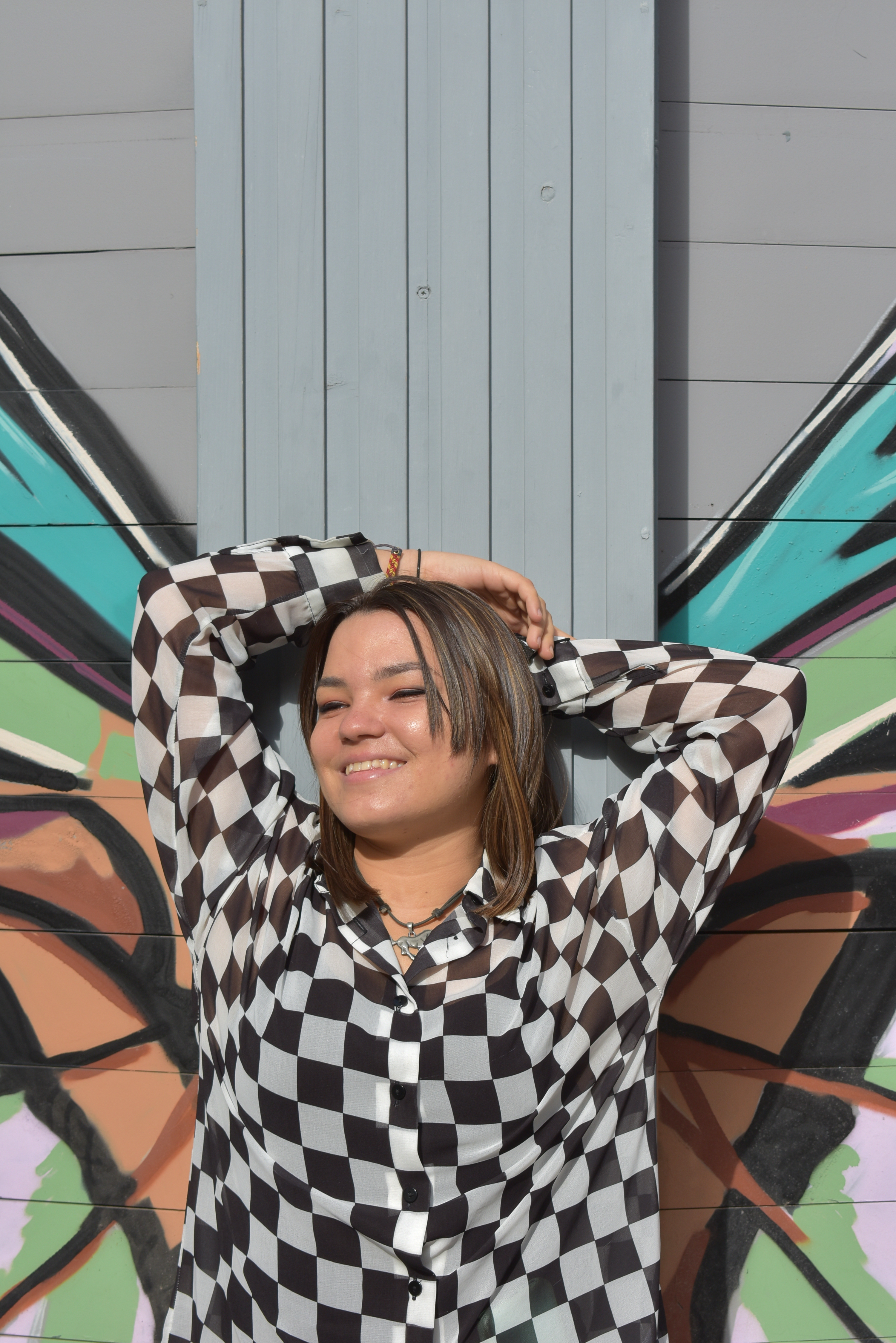 chica posando con un grafitti de alas de mariposa